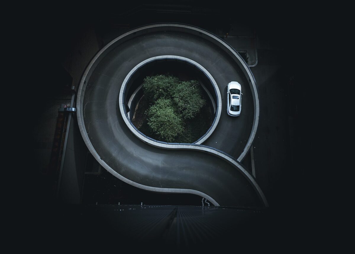En bil som kjører i sirkel på vei opp til en parkeringsgarasje, fotokunst veggbilde / plakat av Tor Arne Hotvedt