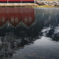 Sju røde naust i Sunndalsøra speiler seg i vannet, fotokunst veggbilde / plakat av Tor Arne Hotvedt