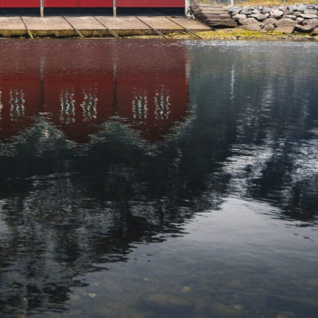 Sju røde naust i Sunndalsøra speiler seg i vannet, fotokunst veggbilde / plakat av Tor Arne Hotvedt